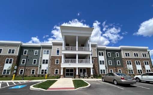 A large apartment complex with a car parked in front.