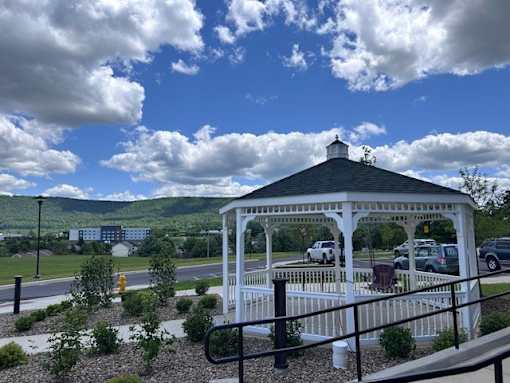 A gazebo is surrounded by a white fence and has a black roof.