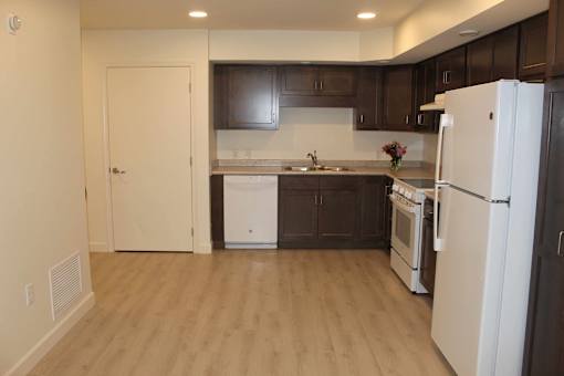 A kitchen with white appliances and brown cabinets.