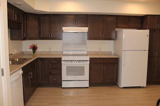 A kitchen with white appliances and brown cabinets.