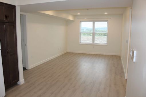 A room with wooden flooring and a window overlooking a field.