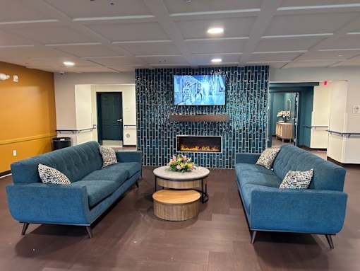 A living room with two blue couches and a fireplace.