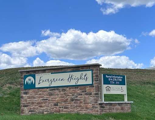 A sign for Evergreen Heights with a phone number and a symbol for wheelchair accessibility.