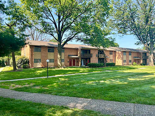 Apartment complex with green grass and trees.