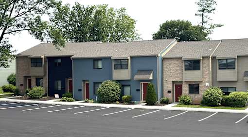 Apartment building with a parking lot in front.