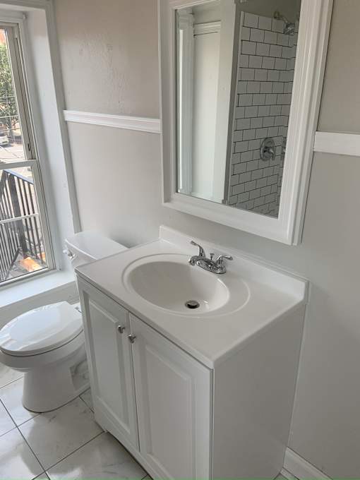 A white bathroom with a toilet, sink, and mirror.