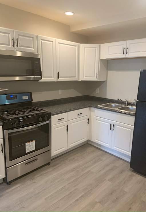 A kitchen with white cabinets and a black refrigerator.