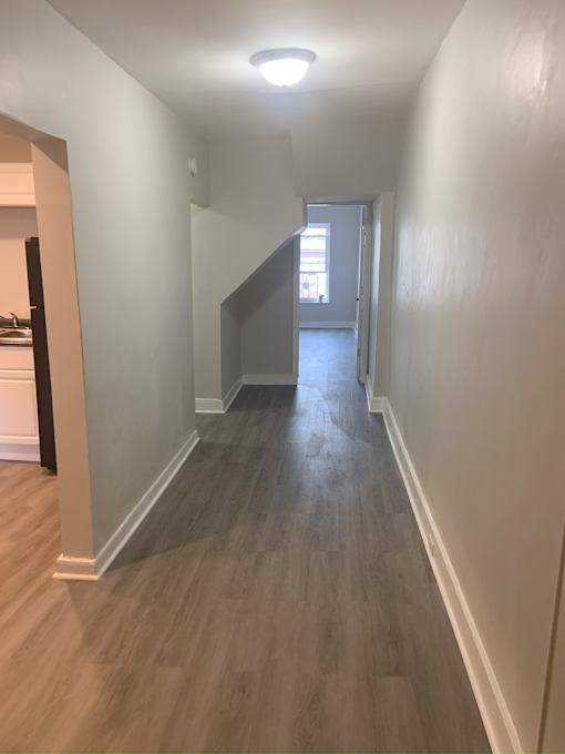 A long hallway with wood floors and white walls.