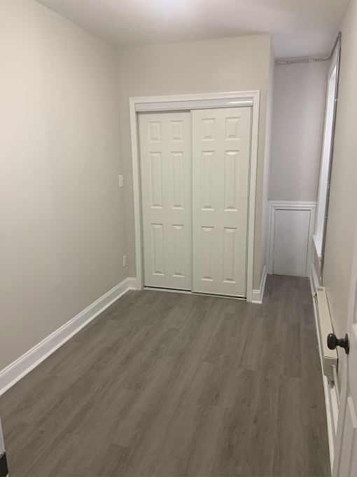 A white door with a black handle is in a room with wood flooring.