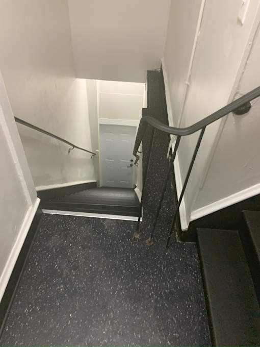 A stairway with a black handrail and a black step.