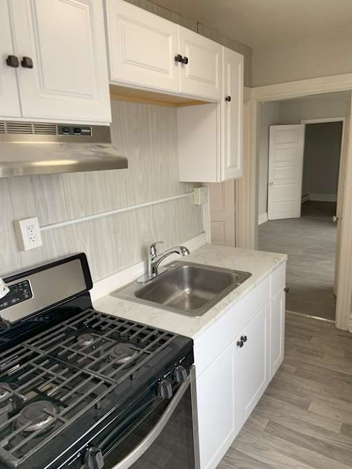 A kitchen with a stove, sink and cabinets.