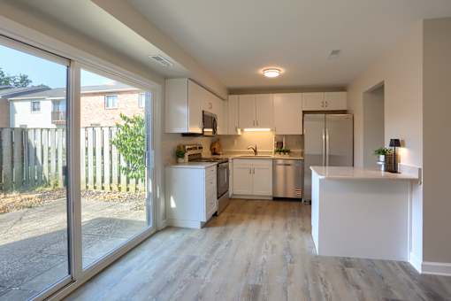 A modern kitchen with white cabinets and a wooden floor.