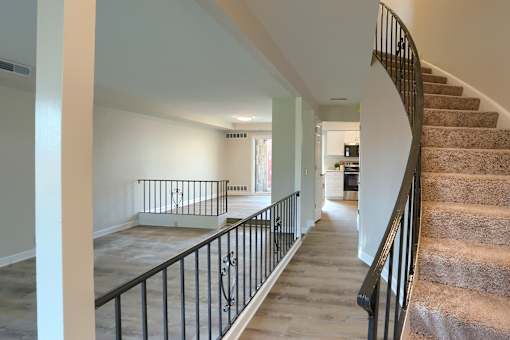 A staircase with a black railing and beige carpeted steps.