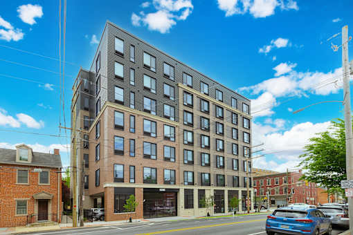 A modern multi-story building with a parking lot in front.
