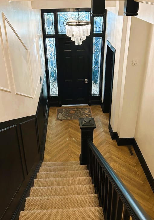 a stairway with a chandelier and a black door