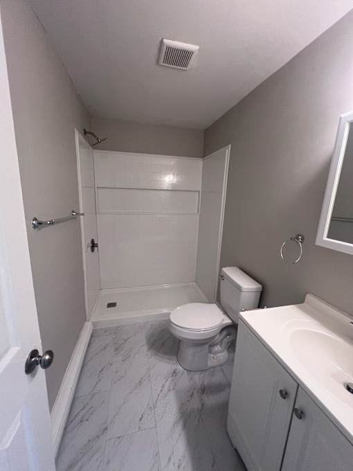 A white bathroom with a toilet, sink, and shower.