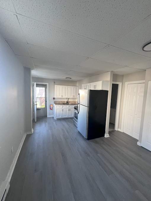 A kitchen with a black fridge and white cabinets.