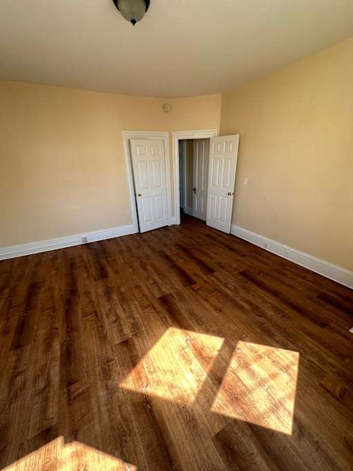 A room with wooden floors and two white doors.