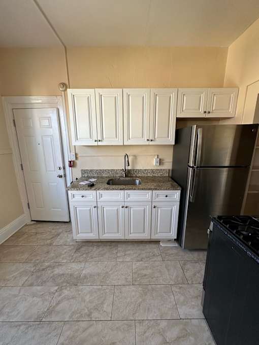 A kitchen with white cabinets and a black dishwasher.