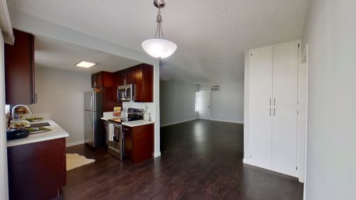 an empty kitchen and living room with wood flooring and white walls
