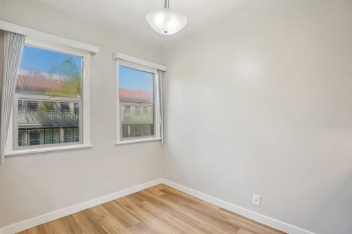 A room with two windows and a wooden floor.