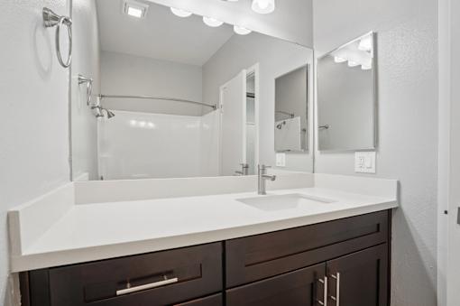 A bathroom with a white sink and brown drawers.