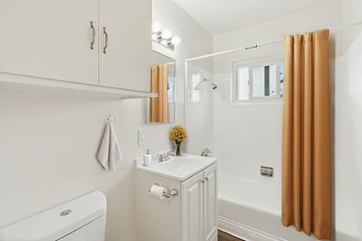 A white bathroom with a toilet, sink, and shower.