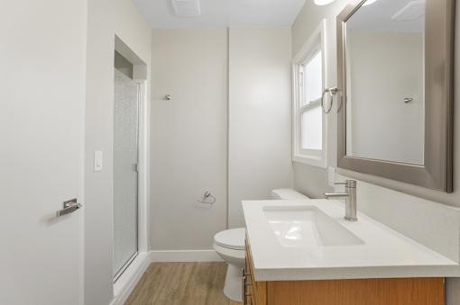 A white bathroom with a toilet, sink, and mirror.