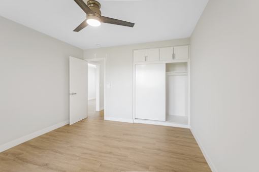 A room with a ceiling fan and wooden flooring.
