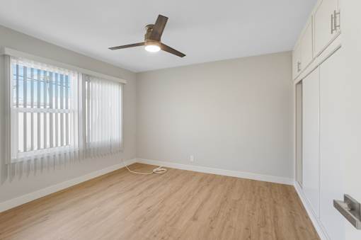 A room with a ceiling fan and wooden flooring.