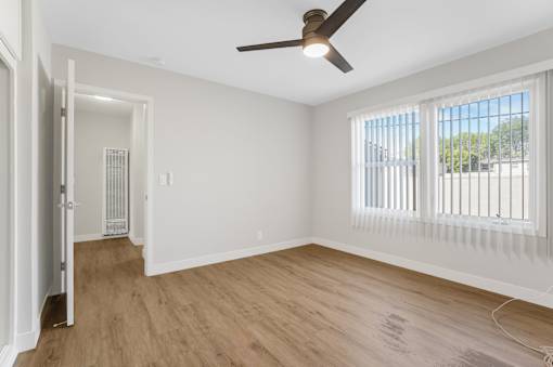 A room with a ceiling fan and a window with blinds.