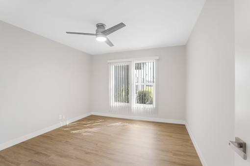 A room with a ceiling fan and a window with blinds.