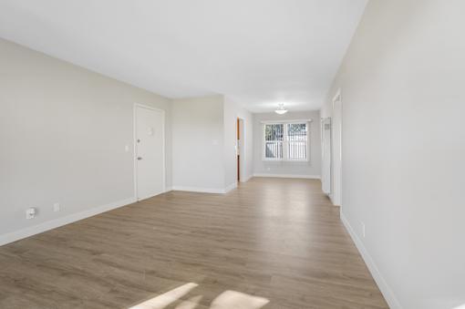 A long, empty hallway with wooden floors and white walls.