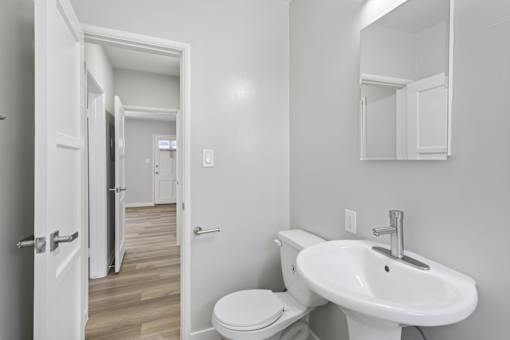 A bathroom with a toilet, sink, and mirror.