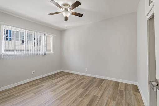 A room with a ceiling fan and wooden flooring.