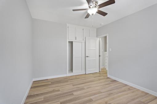 A room with a ceiling fan and wooden flooring.