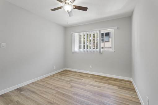A room with a ceiling fan and a window with blinds.