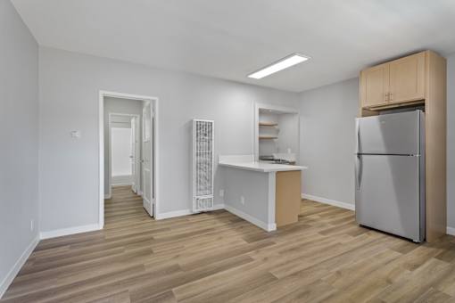 A kitchen area with a refrigerator, a counter, and a pantry.