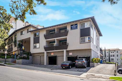 A two-story apartment building with a garage and cars parked in front.