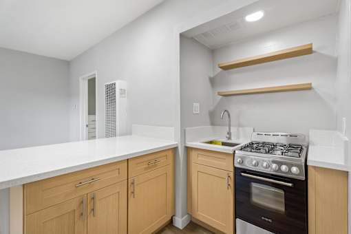 A kitchen with a white countertop and wooden cabinets.