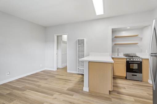 A kitchen with a white countertop and wooden floors.