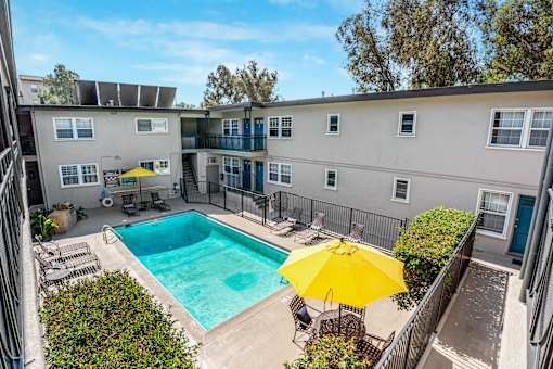 A yellow umbrella is on a chair by a pool.