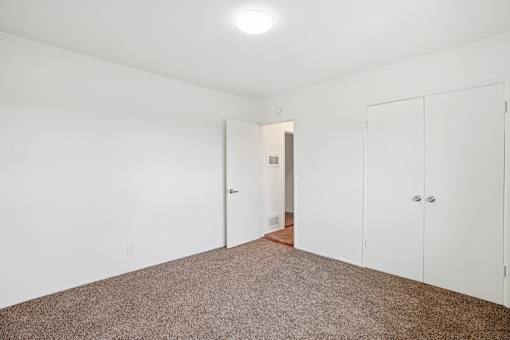A room with white walls and a brown carpet.