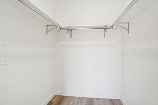A white wall with a wooden floor and a metal pipe on the ceiling.