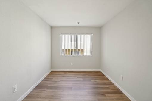 A room with wooden floors and a window with blinds.