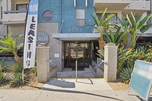 A blue building with a sign that says "NOW LEASING" in front of it.