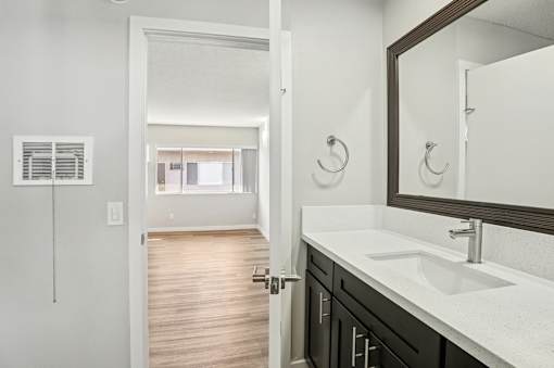 A bathroom with a sink, mirror, and a door.