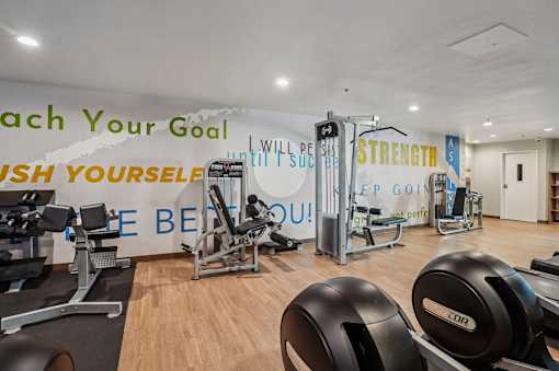 A gym with a variety of equipment and motivational phrases on the wall.