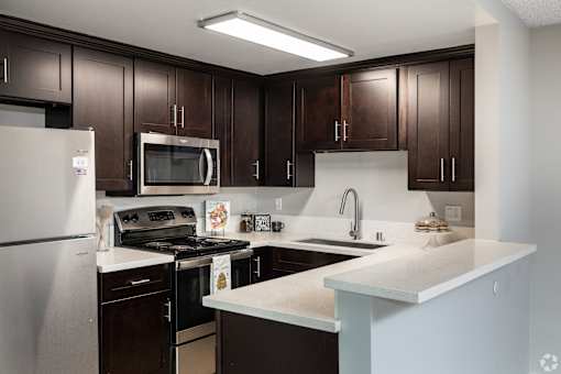 A kitchen with dark brown cabinets and a white counter.