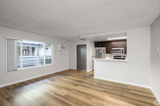 A spacious room with wooden flooring and a kitchenette.